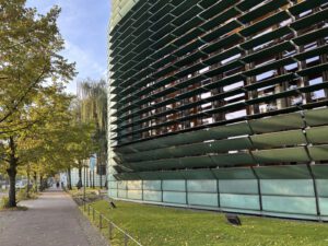 Green building facade for the Nordic Embassies in Berlin with trees and pedestrian route next to Main Street.