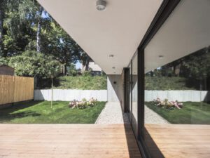 Wooden deck patio surrounded by greenery, including a Japanese cherry tree and bamboo plants