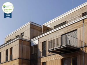Exterior view of the Climate Positive Living complex in Berlin, featuring a hybrid construction with a timber facade