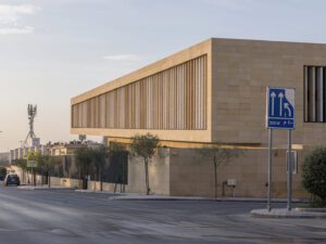 Perspective view of sand brick building Assila Investment HQ in Riad with signal tower at the back.