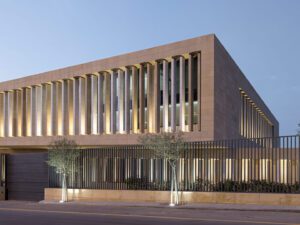 Close up of sand brick building Assila Investment HQ in Riad with louvers and lighting.