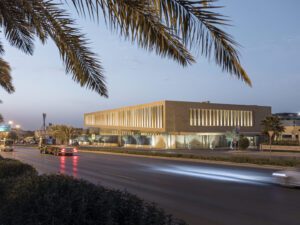 evening view of sand brick building with louvers of Assila Investments HQ from across the road.