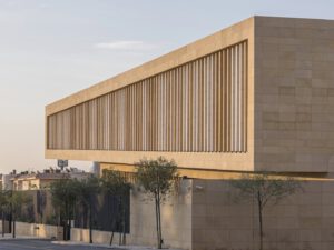 Sand brick building with louvers and trees for Assila Investment HQ in Saudi Arabia