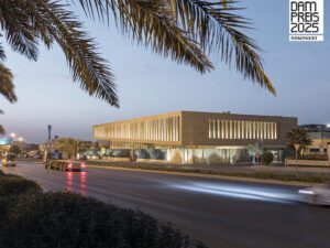 New sandstone building Assila HQ with palm trees and DAM Preis nomination logo.