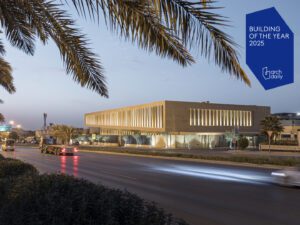 New sandstone building Assila HQ with palm trees and Archdaily logo in blue